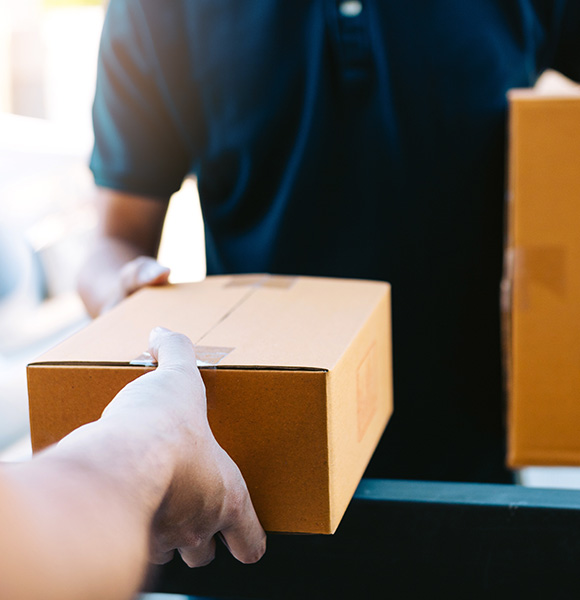 person handing over a cardboard box during delivery process to another person receiving it with focus on interaction and logistics of three packages